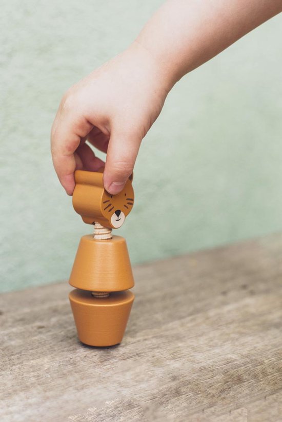 Kinderhand draait de kop van een Trixie houten schroefdier vast